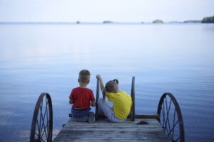 foto di due ragazzi seduti sul ponteggio di un molo