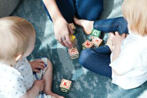 Copertina di Una buona partenza nella vita per tutti - un bambino e una bambina giocano con dei cubi con scritte sopra lettere e numeri insieme ad un genitore