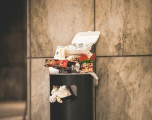 Un cestino della spazzatura pieno di cibo e cartacce - spreco alimentare