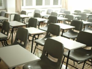 Copertina di La scuola brucia - Una classe vuota piena di banche e sedie bianchi