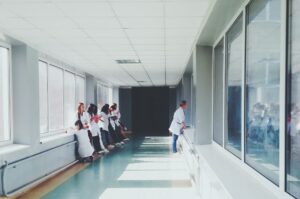 Corridoio di un ospedale con infermiere. Immagine di copertina di un articolo di Franca Maino che presenta la sessione 3 della conferenza Espanet Italia 2023 dedicata ai sistemi sanitari in transizione