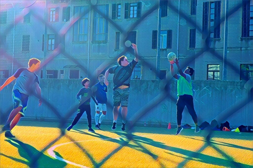 Ragazzi che giocano su un campo sportivo. Immagine di copertina di un articolo di Secondo Welfare che racconta della comunità di pratica nata intorno al progetto "Ogni luogo un incontro", sviluppatosi nella provincia di Monza e Brianza grazie alla locale fondazione di comunità